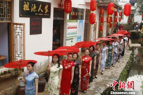 中國僑網(wǎng)圖為旗袍表演隊走過村莊?!〕滔蜿枴z