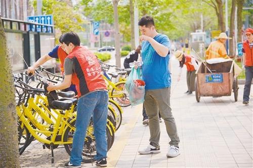 中國僑網(wǎng)義工在整理共享單車,。郭永樂 攝