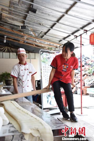 中國僑網郭煒蘭騎在搟面杖上搟面,,上下跳著就像在跳舞一般?!£慅埳健z