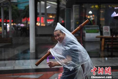 中國僑網(wǎng)圖為重慶街頭的力哥利用塑料袋自制雨衣遮雨,。 陳超 攝