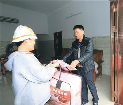中國僑網(wǎng)1月11日,,瓊中黎族苗族自治縣民政局聯(lián)合相關部門為該縣營根鎮(zhèn)南豐村困難群眾(左)送棉被。通訊員 林學健 攝