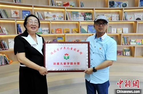 中國僑網(wǎng)圖為福建省少年兒童圖書館館長鄭衛(wèi)光(右)向新星兒童學園授福建省少年兒童圖書館新星兒童學園分館牌匾?!埍蟆z