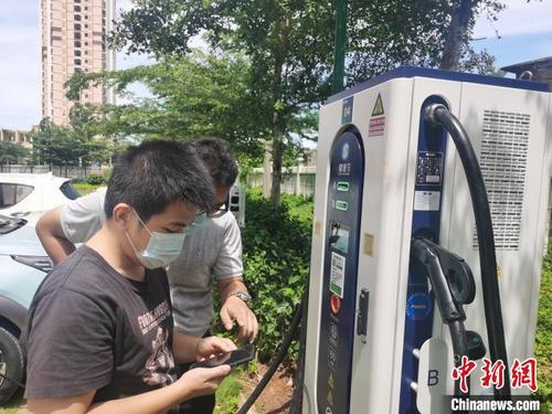中國僑網(wǎng)海口一小區(qū)電動(dòng)汽車車主在研究充電樁,?!↑S藝 攝