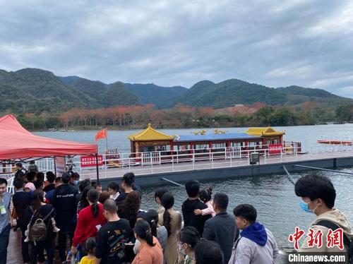 中國僑網(wǎng)海南昌化江畔木棉賞花碼頭,游客排隊乘船漫游賞木棉。 符宇群 攝