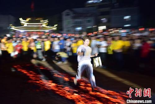 中國(guó)僑網(wǎng)8月14日,,游客勇敢穿過(guò)經(jīng)鹽等處理過(guò)的炭火(勿模仿),。代表紅紅火火?!堺惥z
