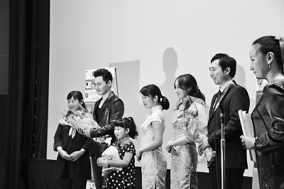 中國僑網(wǎng)圖為《洋妞到我家》導(dǎo)演陳剛(右二)和小演員陳一諾在放映儀式上接受觀眾獻(xiàn)花,。(謝宗睿 攝)