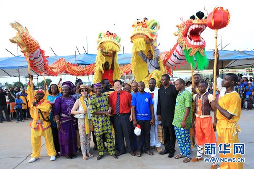 中國僑網(wǎng)在“2015貝寧第六屆歡樂春節(jié)”廣場巡演活動現(xiàn)場,,貝寧青年,、體育和娛樂部長薩福(前排左四)與龍獅隊員等合影。