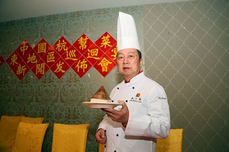 中國僑網(wǎng)迷宗菜”創(chuàng)始人胡忠英展示招牌菜“金牌扣肉”,。(美國《僑報》/宋?D 攝)