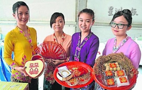 中國僑網(wǎng)美娘們向來賓展示土生華人婚嫁儀式上所采用,、代表吉祥的物品及食品。(馬來西亞《星洲日報》)