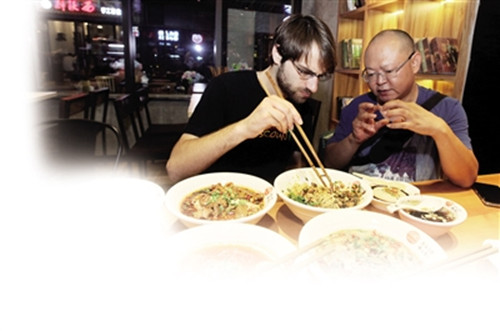 昨日(17日),,小面達(dá)人李杰平(右)陪著來自美國的費(fèi)哲明品嘗重慶小面。(雷鍵