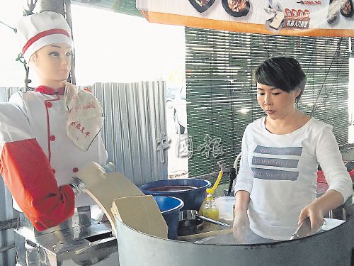 機(jī)器人站在爐子旁削面,,王麗萍撈起烹煮,。(馬來(lái)西亞《中國(guó)報(bào)》/張書樂