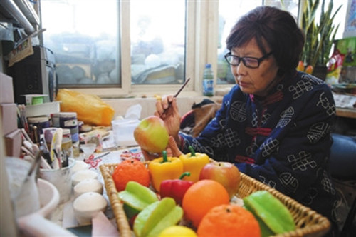 23日,,西城區(qū)非物質(zhì)文化遺產(chǎn)蠟果制作傳承人劉秀華的家中,劉秀華正在制作水果蔬菜,。(李飛