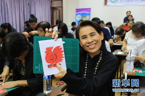 中國(guó)僑網(wǎng)22日,,曼谷市教育局副局長(zhǎng)塔妮達(dá)在活動(dòng)現(xiàn)場(chǎng)展示自己的“雄雞”剪紙作品,。