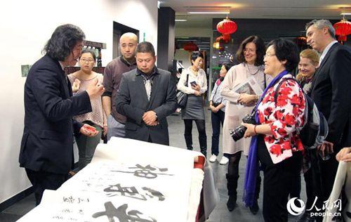 中國僑網(wǎng)北京風(fēng)情油畫家王繼民(左1)現(xiàn)場表演書法,。人民網(wǎng)記者管克江攝