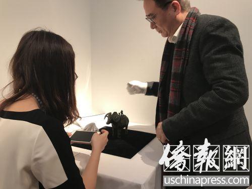 中國(guó)僑網(wǎng)一位私人收藏家正在與展館人員探討青銅羊觥。(美國(guó)《僑報(bào)》/李莎菲 攝)