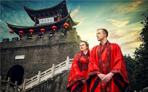 中國僑網(wǎng)在夕陽下的古佛寺前,克里斯和吉瑪身著朱紅色寬袍廣袖的漢服幸福地依偎在一起。(新華網(wǎng)摘自網(wǎng)絡(luò)圖片)