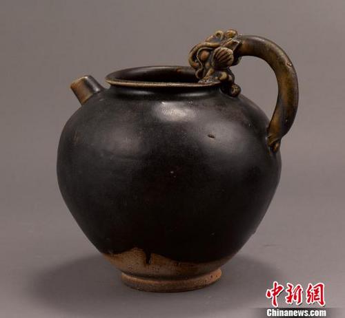 中國僑網(wǎng)圖為展出的唐代鞏縣窯黑釉龍柄壺 李映民 攝