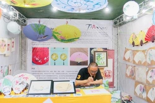 中國僑網(wǎng)手工藝人在繪畫扇面,。(美國《僑報(bào)》/思懿 攝)