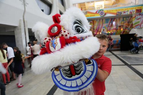 中國(guó)僑網(wǎng)6月22日,,在白俄羅斯首都明斯克,一個(gè)孩子手舉舞獅道具 魏忠杰攝