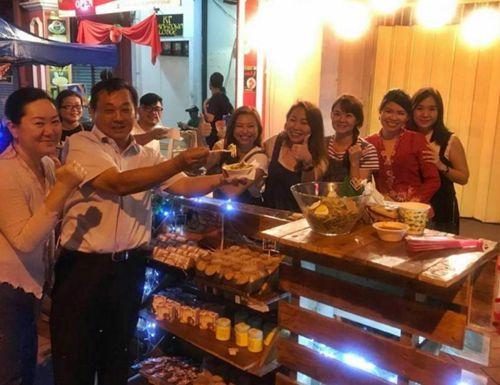 中國僑網(wǎng)馬華登州聯(lián)委會主席杜振耀(左二)光顧華人黃艷莉(右五)和好友們經(jīng)營的攤口,,大贊她們的食物可口,。(馬來西亞《星洲日報》)