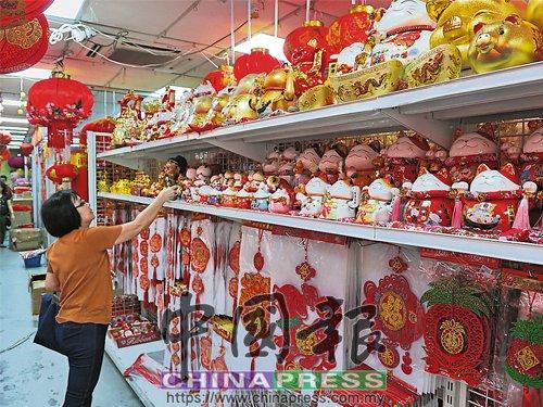 中國僑網(wǎng)商場貨架上擺滿狗年飾品,民眾仔細(xì)挑選,。(馬來西亞《中國報(bào)》)