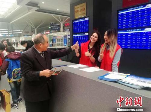 中國(guó)僑網(wǎng)鄭州東站候車(chē)大廳內(nèi)一位老人向兩名外國(guó)留學(xué)生志愿者伸出大拇指點(diǎn)贊,?!Ⅸi 攝