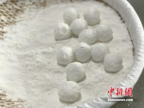 中國僑網(wǎng)做元宵時,,首先要將餡料做好,沾上水,,再投進盛滿糯米粉的笸籮內(nèi)搖,。中新網(wǎng) 吳濤 攝