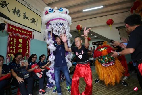 中國僑網(wǎng)博文中學(xué)學(xué)生林柏恩(左)參觀新加坡精武體育會時,在師傅的指導(dǎo)下舞獅,。(新加坡《聯(lián)合早報(bào)》/梁麒麟 攝)