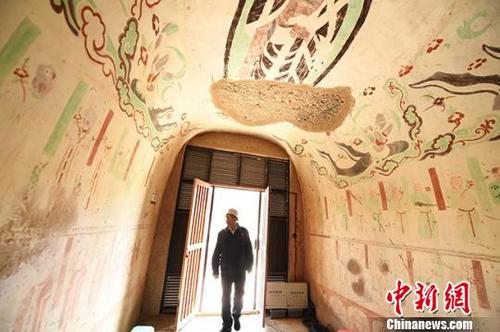 中國僑網(wǎng)8月上旬,,甘肅敦煌室外的氣溫高達(dá)30多度,敦煌研究院“高齡”修復(fù)師李云鶴推開窟門,,走進(jìn)洞窟,。 楊艷敏 攝