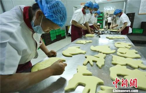 中國(guó)僑網(wǎng)9月18日,在甘肅張掖一家超市的主食加工車(chē)間,,工作人員在制作“土月餅”,。 王將 攝