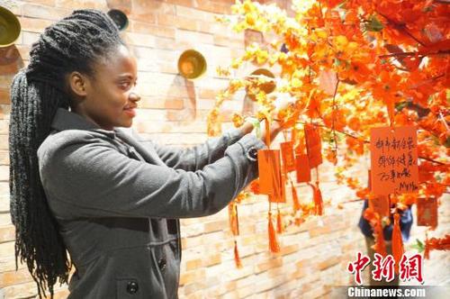 中國(guó)僑網(wǎng)圖為外國(guó)友人在祈福樹上掛上祈福牌,。 韓章云 攝