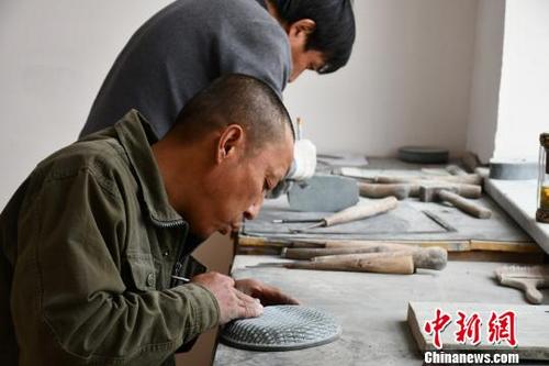 中國僑網(wǎng)圖為村民在扶貧車間里雕刻洮硯?!∥航瘕垺z