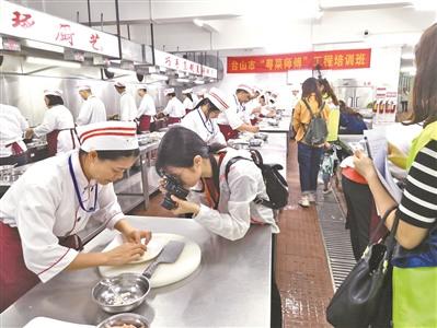 中國僑網(wǎng)臺山廣東廚藝技工學(xué)?!盎洸藥煾怠惫こ膛嘤?xùn)班學(xué)員正在進(jìn)行烹飪練習(xí),。