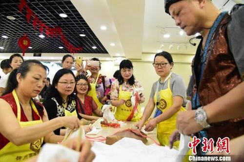 中國僑網(wǎng) 馬踐在講解捆扎法的操作要點(diǎn),,旁邊的市民拿出手機(jī)進(jìn)行記錄,?!⊥跻哉铡z