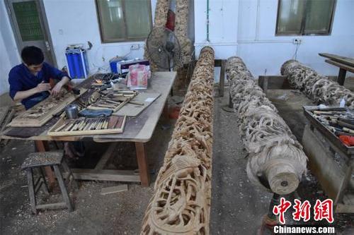 中國僑網(wǎng) 經(jīng)過木雕藝人的巧手雕刻,祥云,、花朵、麒麟,、龍等圖案逐漸顯現(xiàn),。 陳龍山 攝