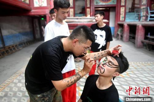 中國(guó)僑網(wǎng)福州錦麟軒八將團(tuán)團(tuán)長(zhǎng)黃杜飛正在給“00后”團(tuán)員畫(huà)臉譜,。 呂明 攝