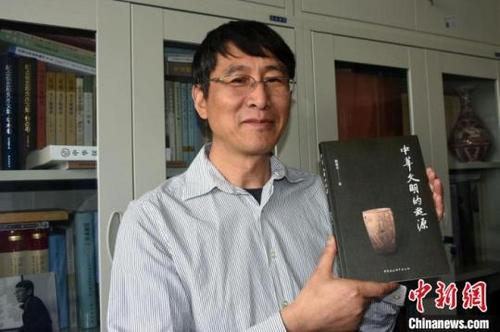 中國(guó)僑網(wǎng)韓建業(yè)教授在辦公室展示《中華文明的起源》新書,?!≈行律缬浾?孫自法 攝