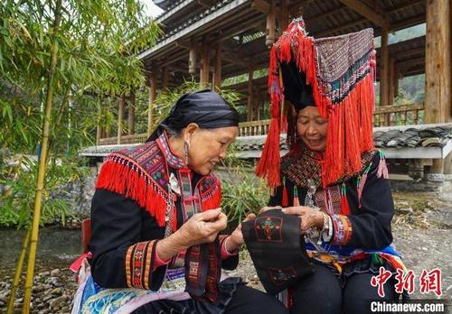 中國僑網(wǎng)圖為鄧正姣(右)在展示瑤族反面刺繡手工技藝,?!√茐魬棥z