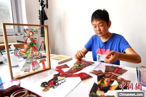 中國僑網(wǎng)圖為王永躍正在將剛剛完成上色的皮影作品組件進行拼接。 劉建斌 攝